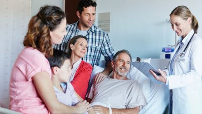 A doctor talking with a patient in bed surrounded by family