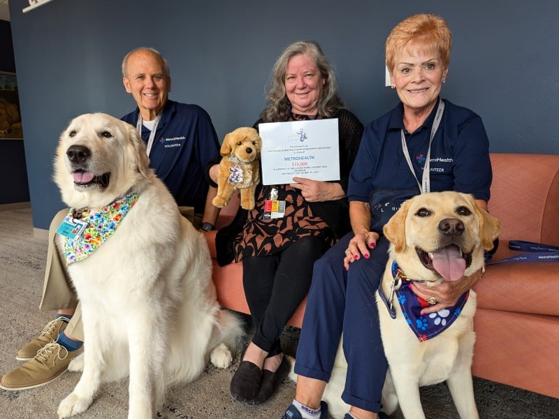 MetroHealth Loving Paws dogs and volunteers with a community donation certificate