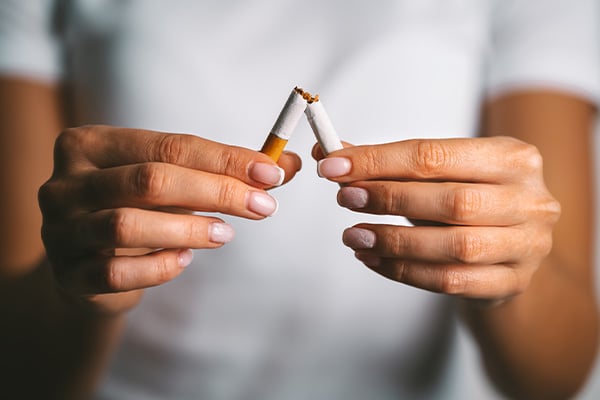Person breaking cigarette in half