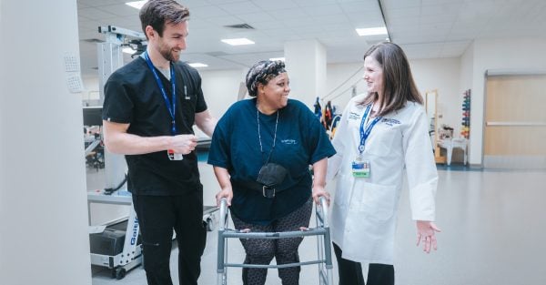 A Rehabilitation patient walking between two MetroHealth providers