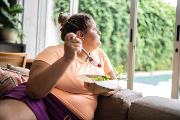 A woman eating a salad and looking pensive