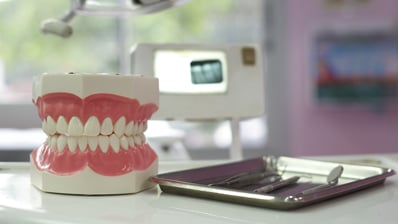 set of false teeth sitting near dental exam tray