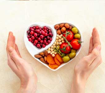 A heart-shaped dish filled with fruit and nuts
