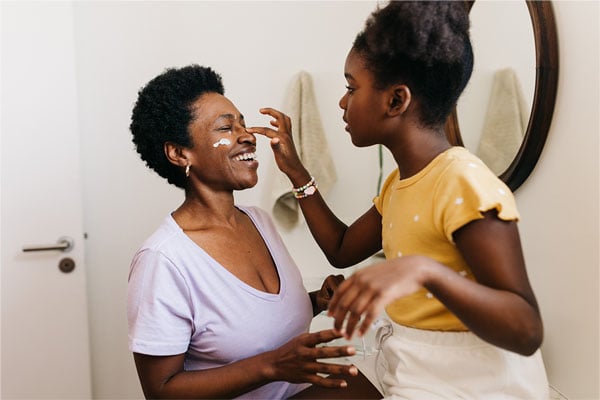 A mother and daughter practicing using skin care products