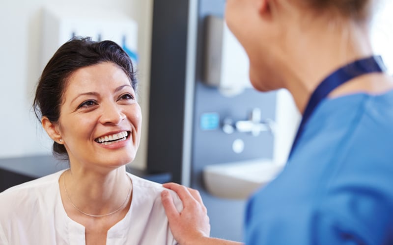 A patient smiling while talking with her doctor