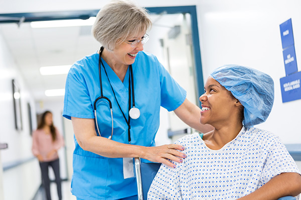 A patient in a hospital gown smiling at her doctor