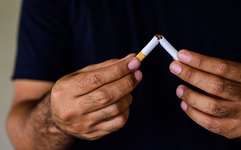 A man breaking a cigarette in half