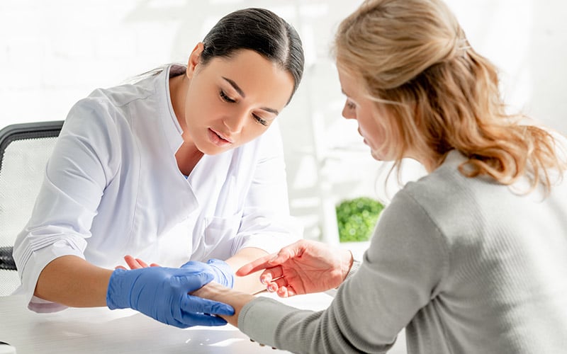 A woman points out a possible trouble spot during a skin screening
