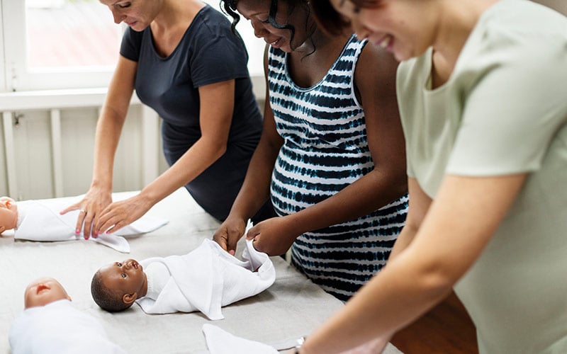 Women learning to swaddle a baby