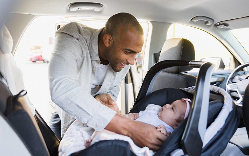 Father putting infant in car seat